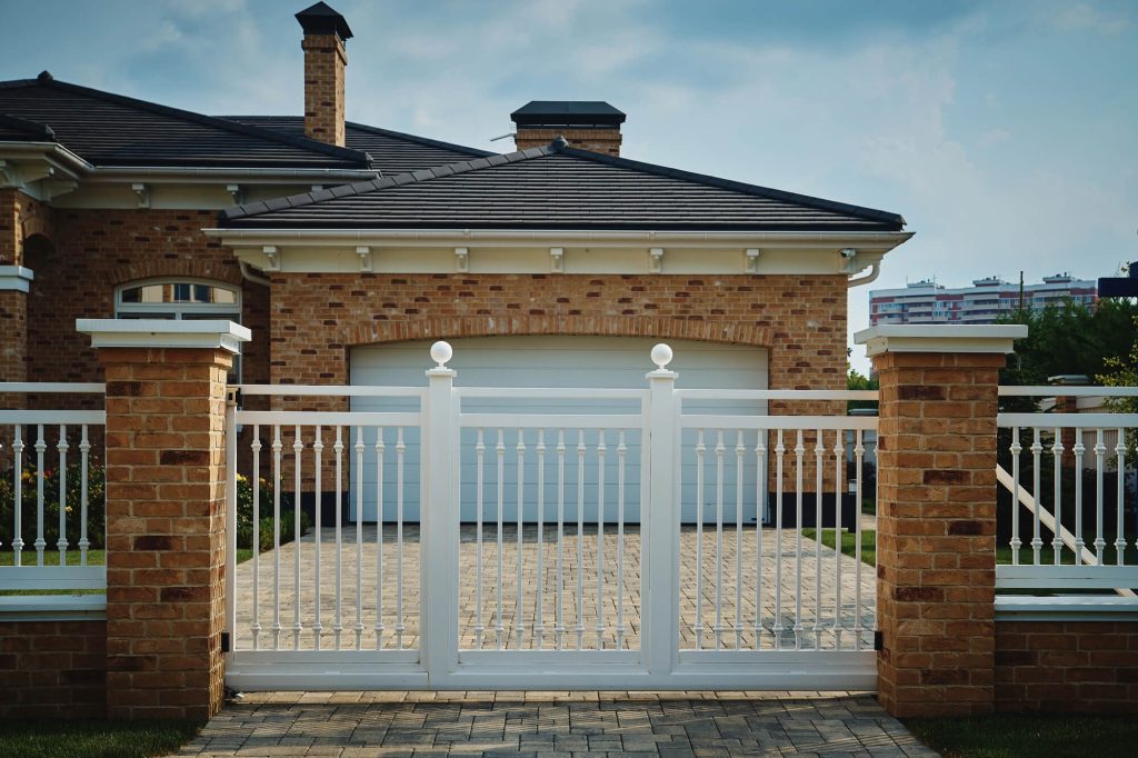 White electric gates and a garage door installed on a Cheshire property by RNM Doors